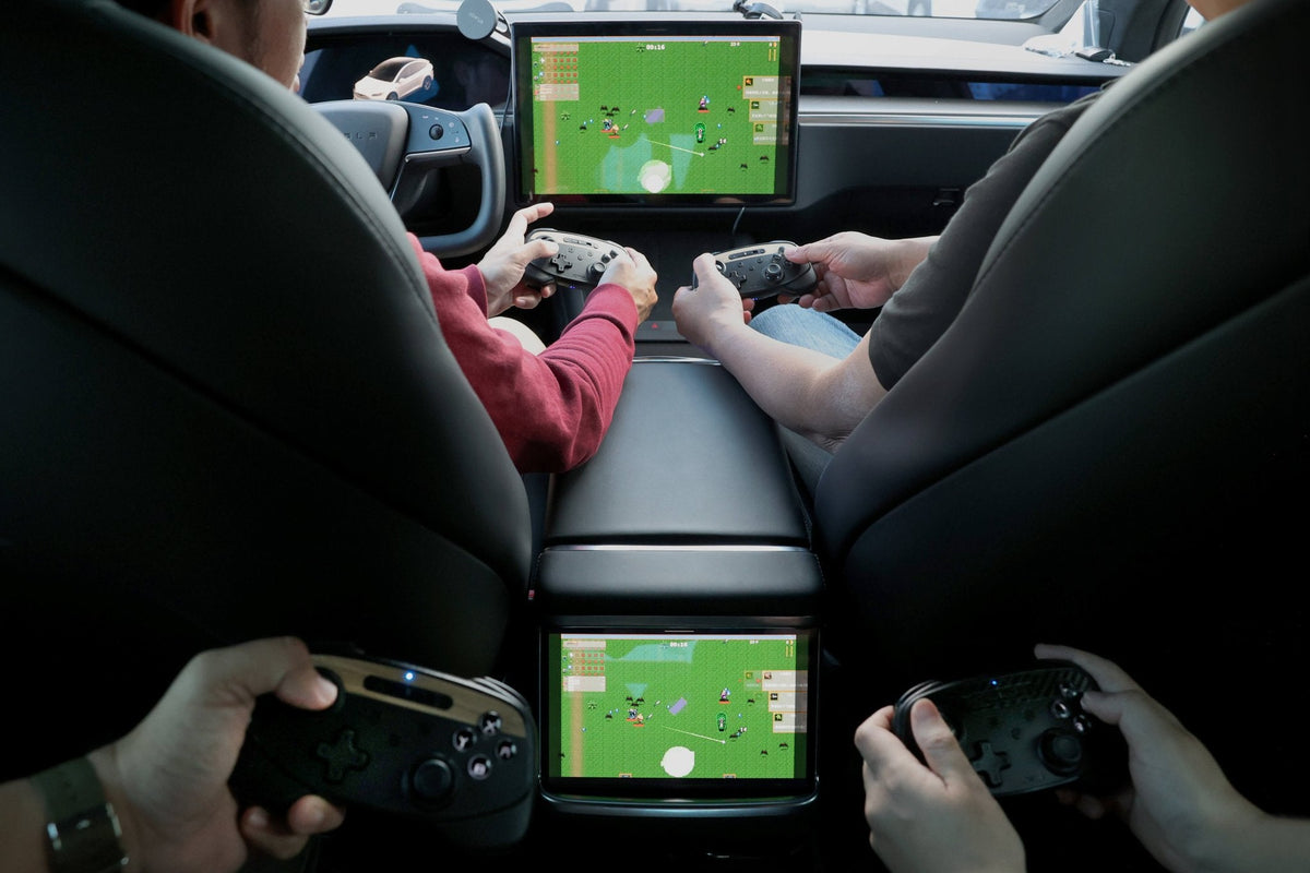 Zwei Insassen spielen mit den Controllern auf dem Bildschirm eines Tesla